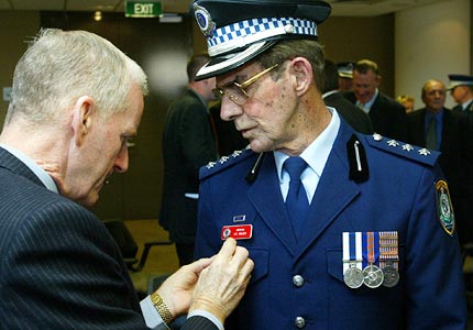 Fair cop ... Inspector Les Walker gets help with his medals from the former inspector Maurice Green. Photo: Peter Morris