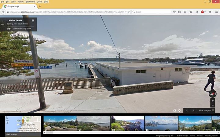 Monument is to the right of the pole and left of the long wall.