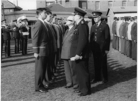 Cadet Barry Symons being addressed by Commissioner Colin J Delaney at a Passing Out Parade, approximately 1957. Next to Cadet Symons is Cadet Norm Maroney, No. 4 in the row is Cadet Terry Mathews. About No. 6 or 7 in the row is Cadet Max Mortimer.