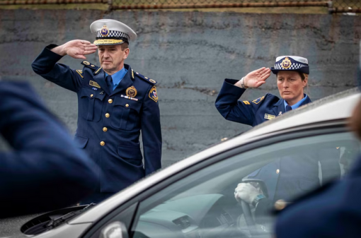 Former Tasmania Police commissioner Darren Hine and Senior Constable Jenny Carlisle salute the hearse at Sergeant Cooke's funeral in 2020.(ABC News: Luke Bowden)